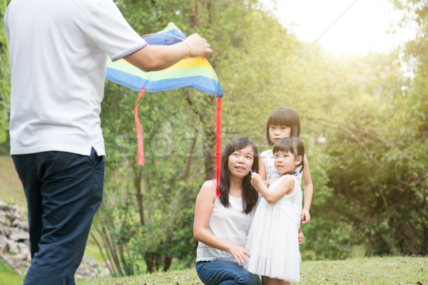 Asian family flying kite outdoors. Stock photo © szefei