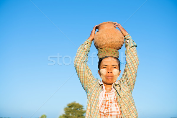 Mature Asian traditional female farmer carrying clay pot on head Stock photo © szefei