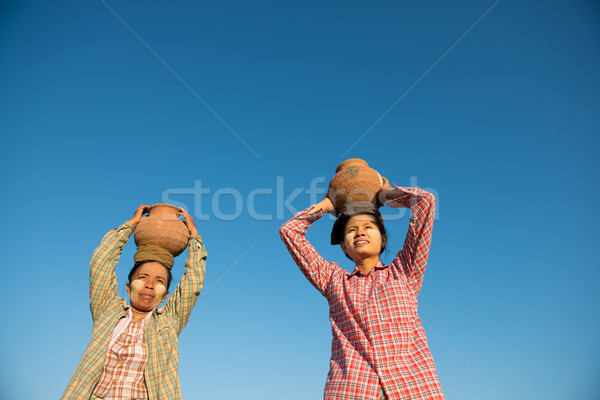 Asian traditional farmers carrying pot on head Stock photo © szefei