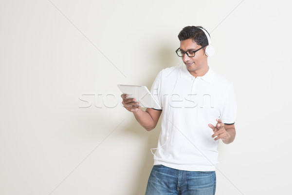 Indian guy playing music with tablet Stock photo © szefei