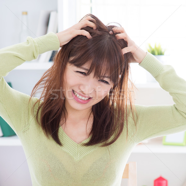 Asian woman scratching itchy head Stock photo © szefei