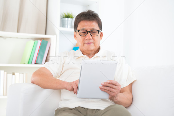 Mature Asian man using tablet pc Stock photo © szefei