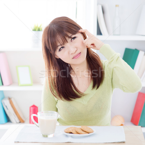 Stock photo: Asian girl thinking while having breakfast