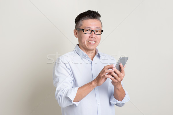 Stock photo: Portrait of mature Asian man using smart phone