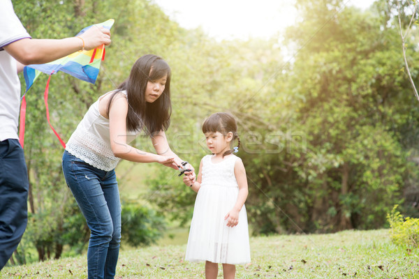 Asian family flying kite at outdoor park. Stock photo © szefei