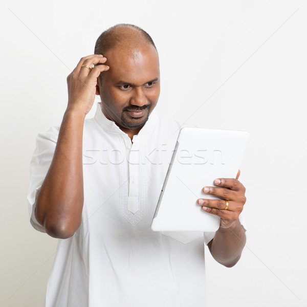 Mature casual business Indian man using tablet pc and scratching Stock photo © szefei