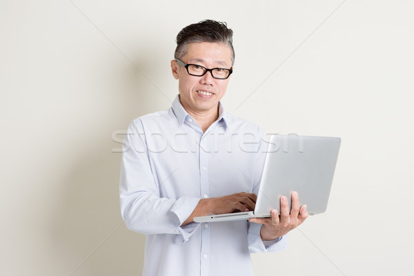 Volwassen asian man met behulp van laptop computer portret Stockfoto © szefei