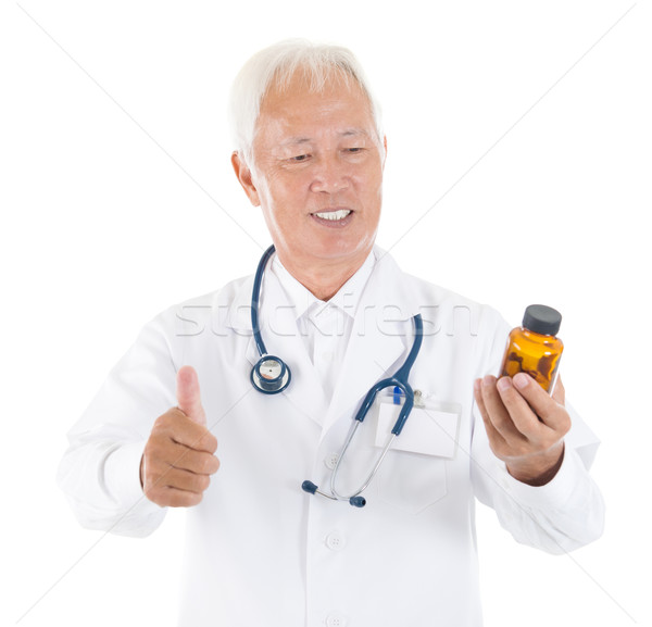 Asian senior medical doctor holding a bottle of pills Stock photo © szefei