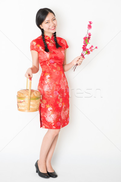 Oriental female in red qipao holding gift basket Stock photo © szefei