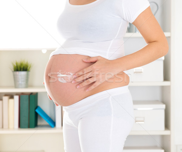 Pregnant woman applying lotion cream Stock photo © szefei