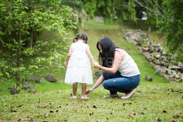 Mother helps little girl wearing shoe at park Stock photo © szefei