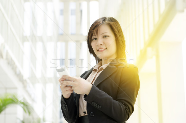 Young Asian business woman texting on smartphone Stock photo © szefei