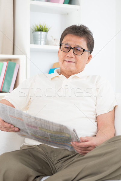 Mature Asian man reading newspaper Stock photo © szefei