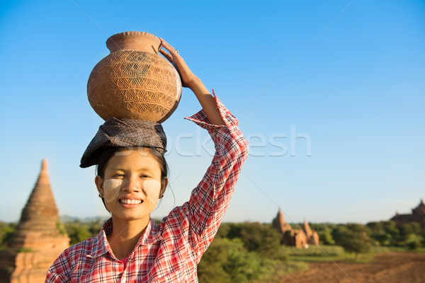 Asian traditional female farmer carrying clay pot on head Stock photo © szefei