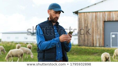 Foto d'archivio: Caucasian Farmer Holding A Mobile Phone