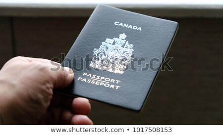 Stok fotoğraf: Persons Hand Holding A Passport Of Canada