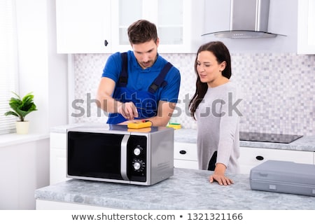 Stock fotó: Male Repairman Repairing Oven In Kitchen