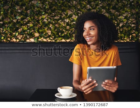 Stok fotoğraf: Happy Young Woman Sitting At A Table Holding Cup Of Espresso Coffee