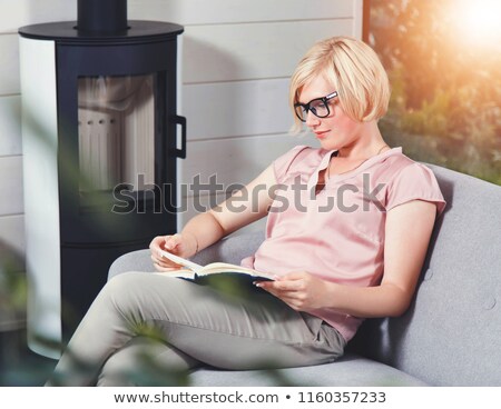 ストックフォト: Blond Lady Reading Book Near Fireplace