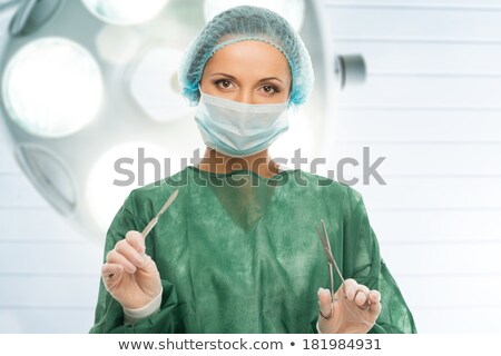Foto stock: Young Woman Doctor With Scalpel And Scissors In Surgery Room Interior