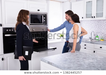 Stock photo: Agent Showing Microwave Oven In House To A Couple