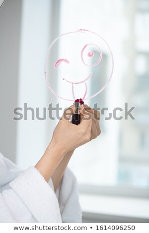 Stock photo: Hand Of Young Female In White Bathrobe Drawing Grimacing Funny Face On Mirror