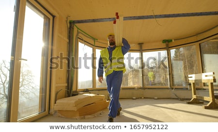 Foto d'archivio: Construction Worker Carrying A Heavy Plank