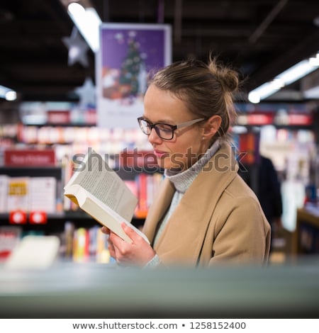 Foto d'archivio: Pretty Young Female Choosing A Good Book To Buy In A Bookstore