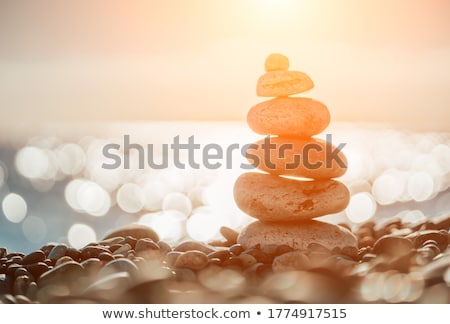 Foto stock: Pyramid Of Sea Pebbles On A Sunny Sand Beach