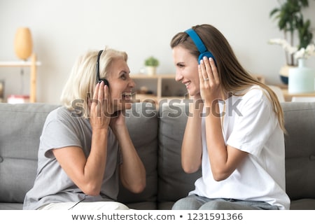 Stock photo: Image Of Two Cheerful Women Wearing Earphones Together And Using