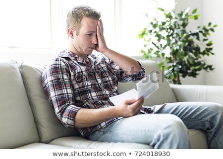 ストックフォト: Shocked Man Holding Some Documents On Sofa Livingroom