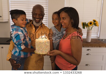 Stockfoto: Front View Of A Happy African American Multi Generation Family Celebrating Birthday With Fire Candle