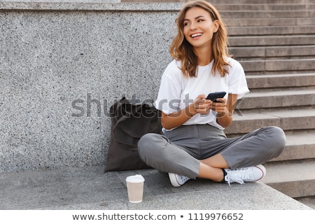 Stock photo: Portrait Of A Smiling Young Woman Sitting With Legs Crossed