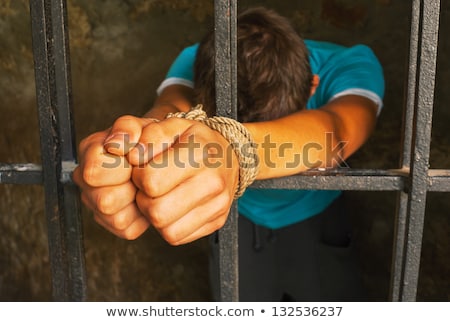 ストックフォト: Man With Hands Tied With Rope Behind The Bars