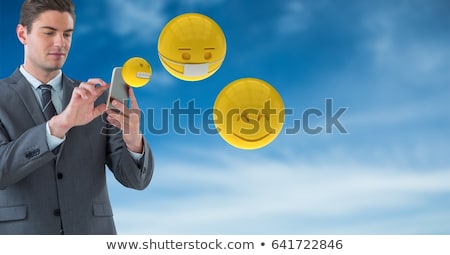 商業照片: Businessman Using Smart Phones While Emojis Flying Against Sky
