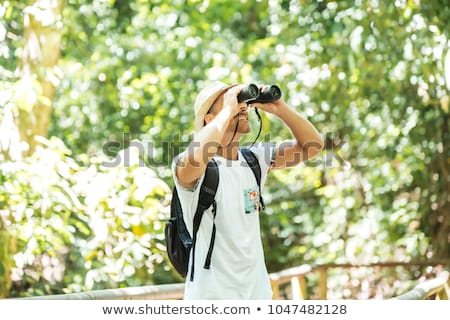 Foto stock: Tourists Man With Binoculars Looking For Something Along The Forest