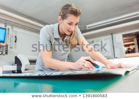 Stock photo: Woman Cutting Signs Or Vinyl Wraps Producing Advertising Materials