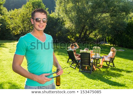 Сток-фото: Man Holding Tongs And Wine Bottle At Garden Party