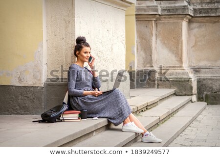 [[stock_photo]]: Pretty Young Worker Sitting On Steps With Phone