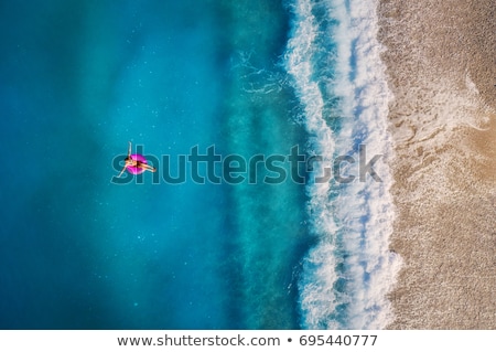 [[stock_photo]]: Aerial View Of Young Woman Swimming On The Pink Swim Ring