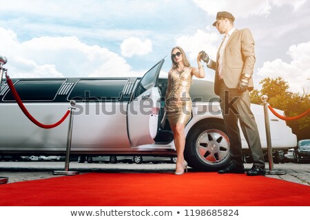 [[stock_photo]]: Driver Helping Vip Woman Or Star Out Of Limo On Red Carpet