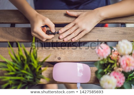 Foto stock: Young Woman Makes Manicure With Gel Polish And Uv Lamp In Pink Shades