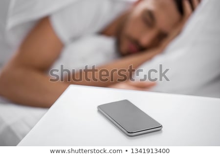 Stock photo: Smartphone On Bedside Table Near Sleeping Man