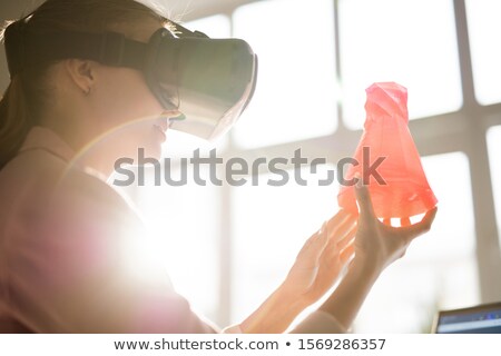 Zdjęcia stock: Young Woman In Vr Headset Holding Red Plastic Object In Front Of Her Face