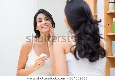 Foto stock: Ulher · jovem · aplicando · loção · no · banheiro