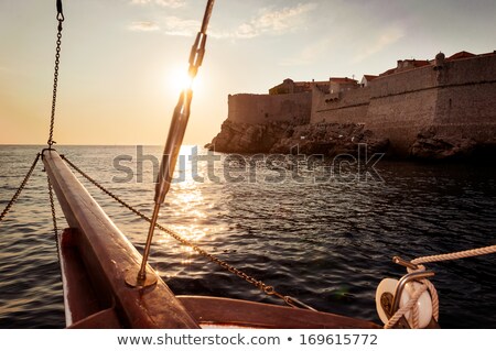 ストックフォト: Old Sailing Ship Sails Into The Sunset Next To The City Walls Of
