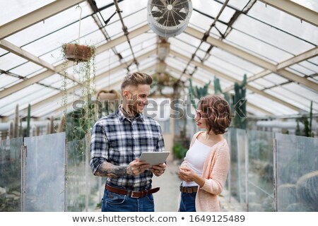 Foto d'archivio: Attractive Man Gardener Standing And Using Tablet