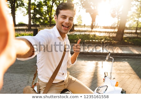 Stockfoto: Excited Young Business Man Walking Outdoors On Scooter Take A Selfie By Camera