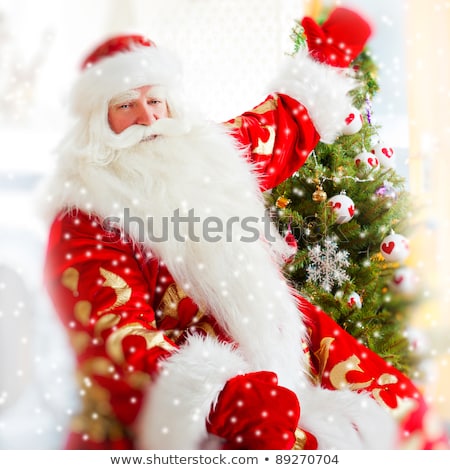 Stockfoto: Santa Sitting At The Christmas Tree Near Fireplace And Looking