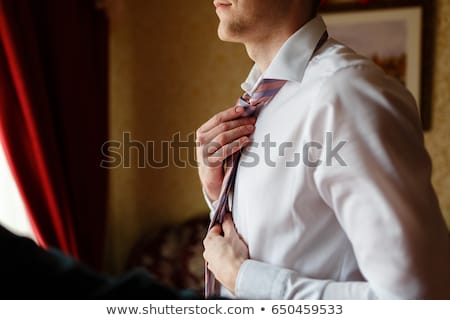 Foto stock: Groom Tying Tie On A White Shirt